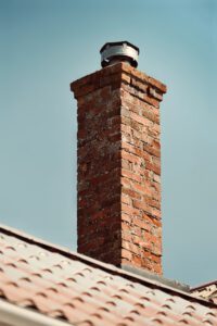 a brick chimney with a weather vane on top of it